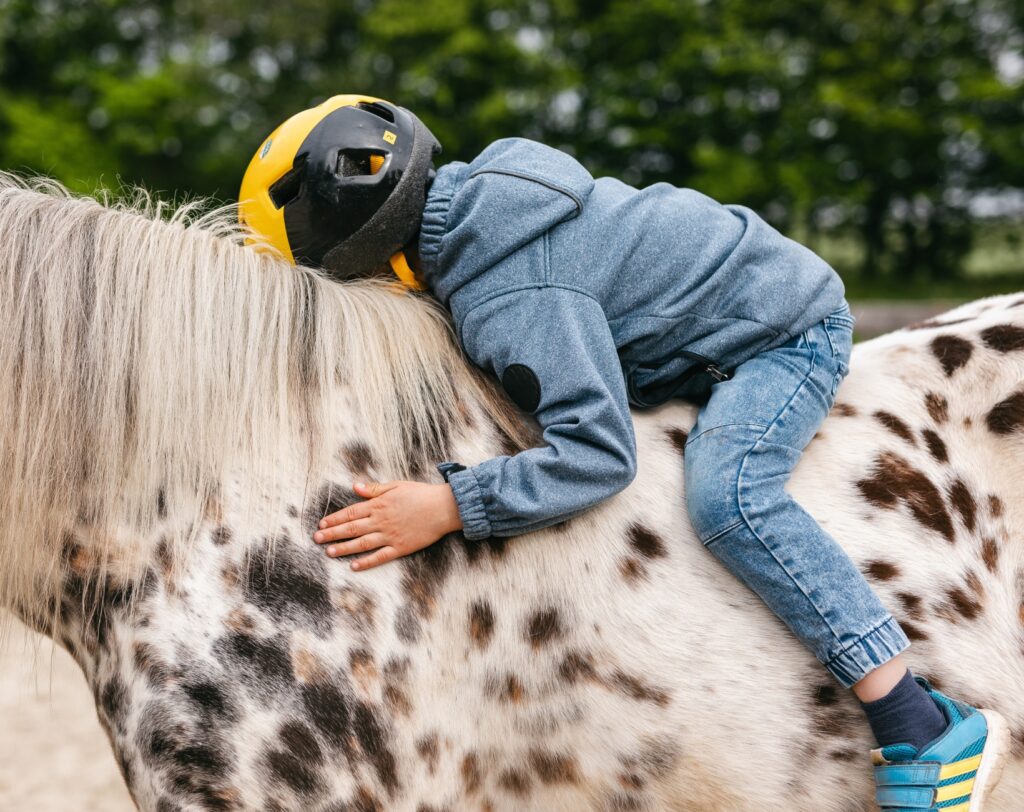 Kind kuschelt mit einem Pferd