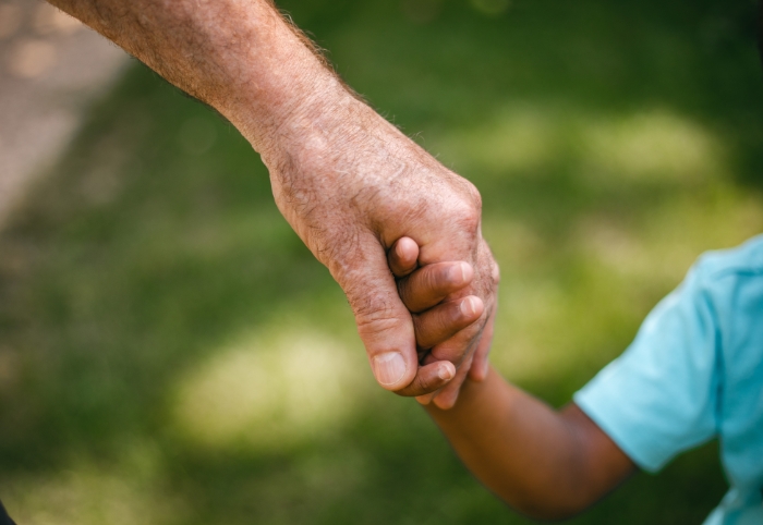 Hand einer alten Person hält die Hand eines Kindes
