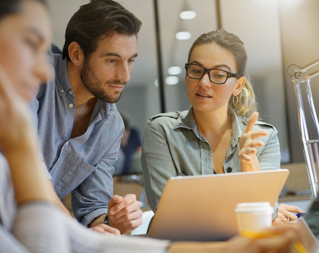 Zwei Personen arbeiten zusammen an einem Laptop
