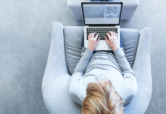 Frau sitzt auf einem Sessel am Laptop